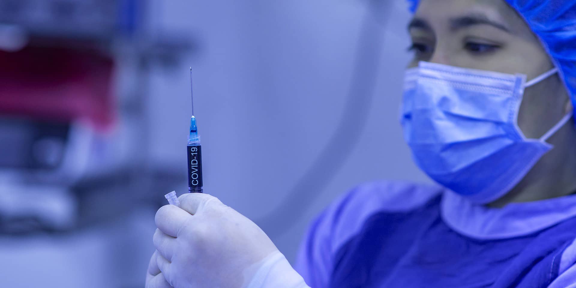 A female nurse holding up a COVID-19 vaccine syringe