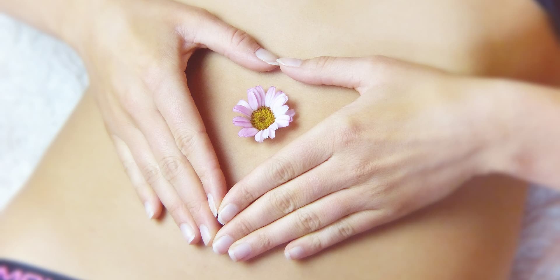 A woman's belly with a pink flower ontop