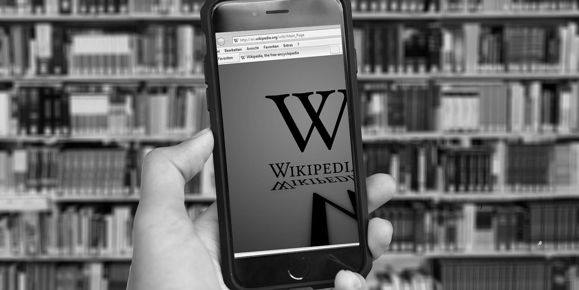 A hand holding a mobile phone with Wikipedia on the screen